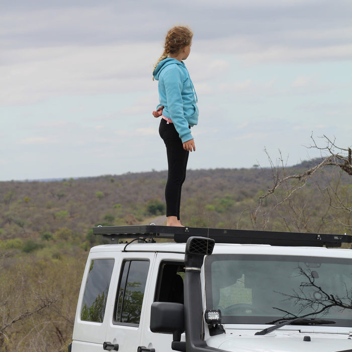 Danyel Kitching standing on the roof rack of a Jeep Wrangler Sahara in Kruger National Park